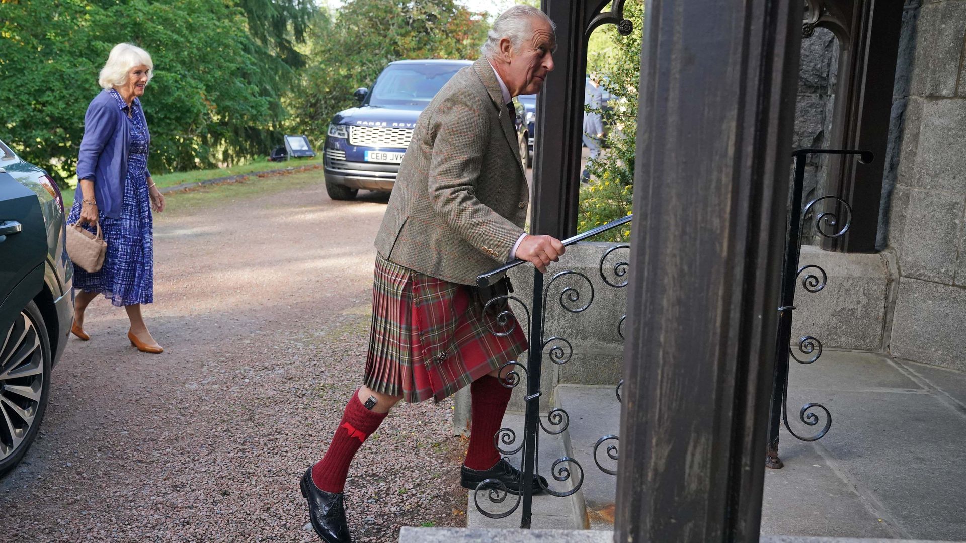 King Charles wearing a kilt, walking up the stairs to attend a church service
