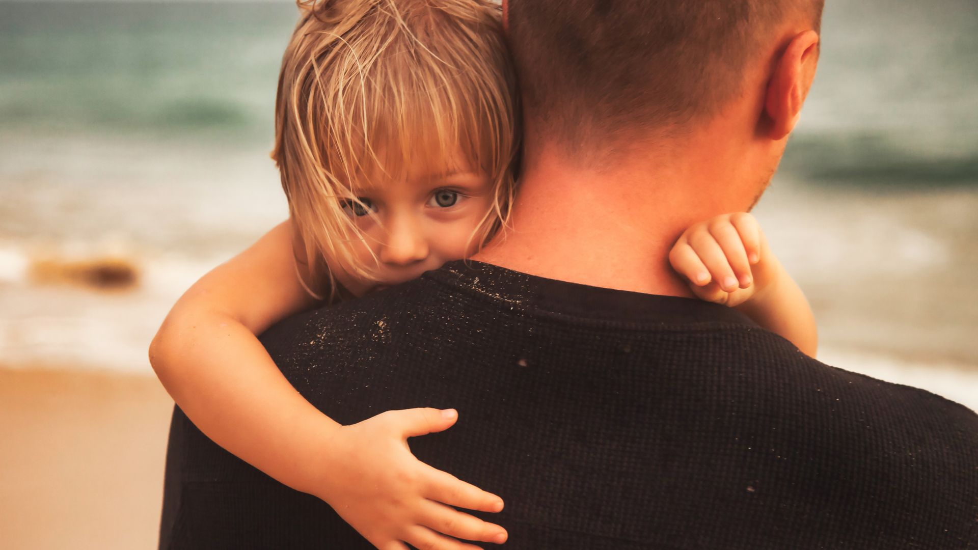 Sad little girl daughter hugging father on the beach