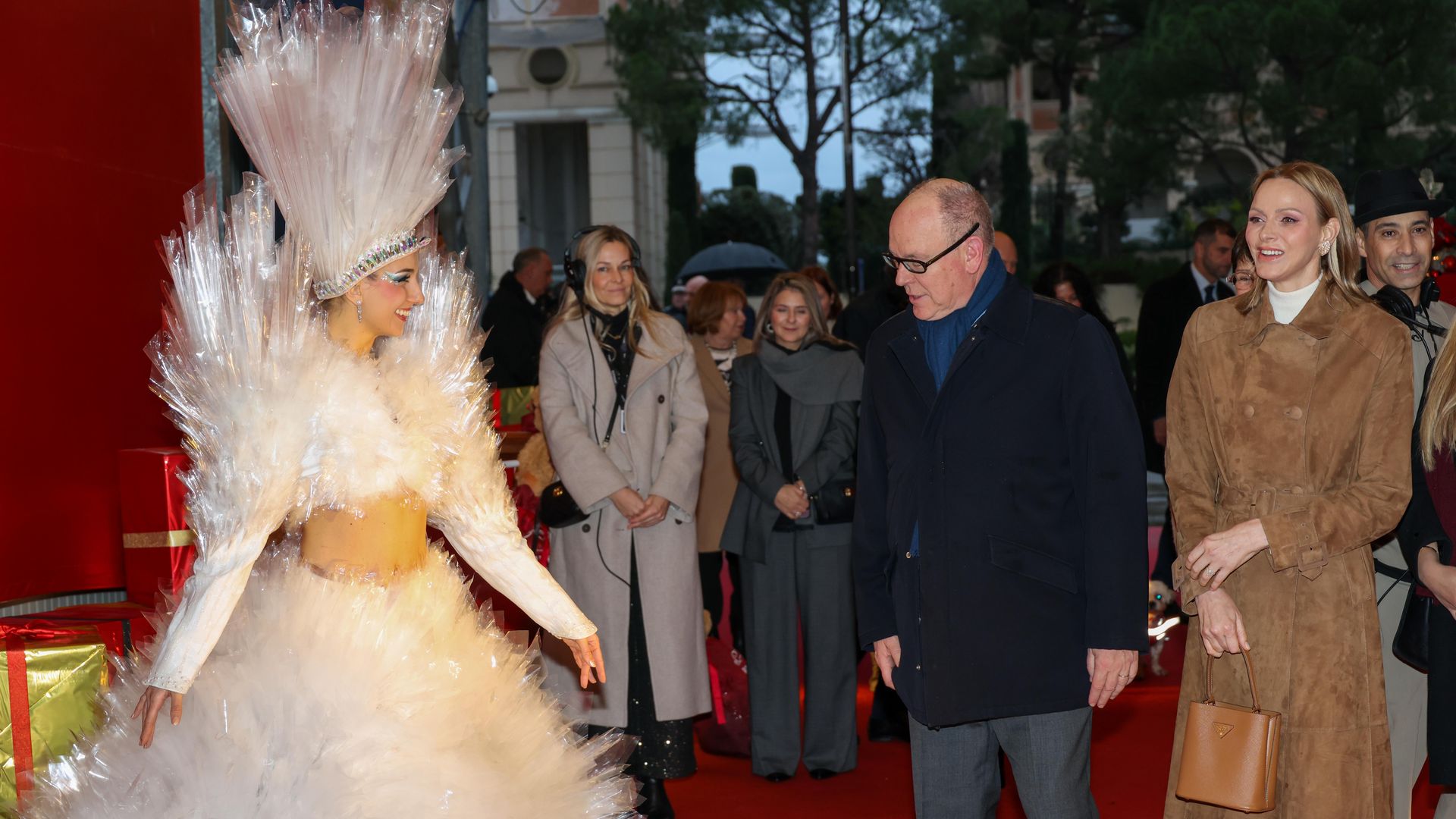Prince Albert and Princess Charlene looking at a woman in a white outfit