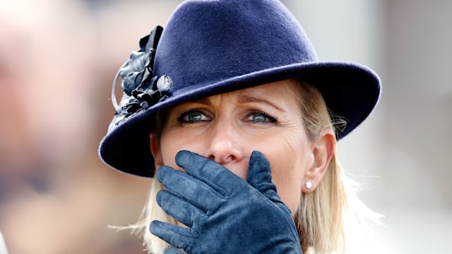 Zara Tindall with her hand over her face in a blue outfit