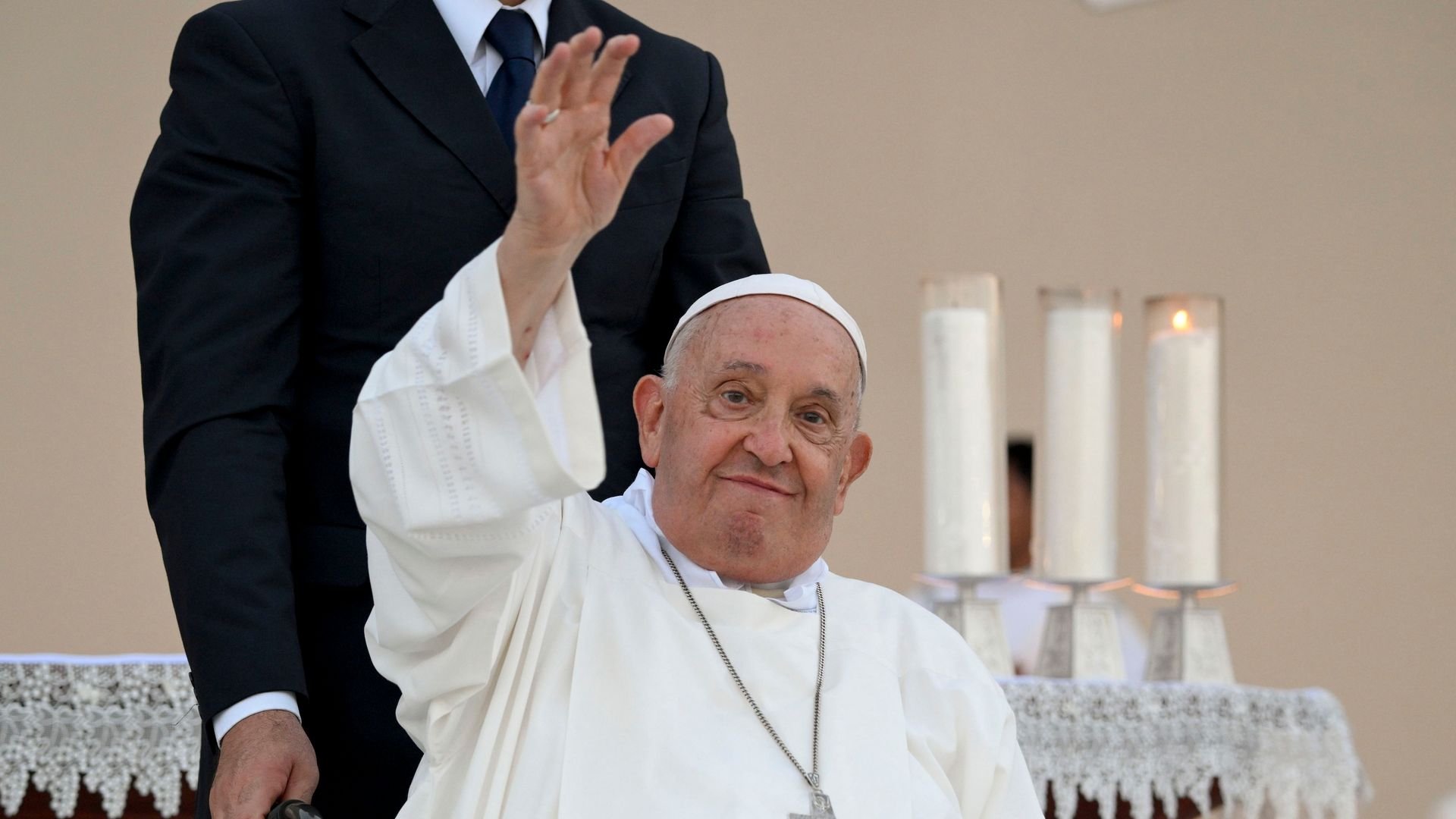 Pope Francis waving from a wheelchair