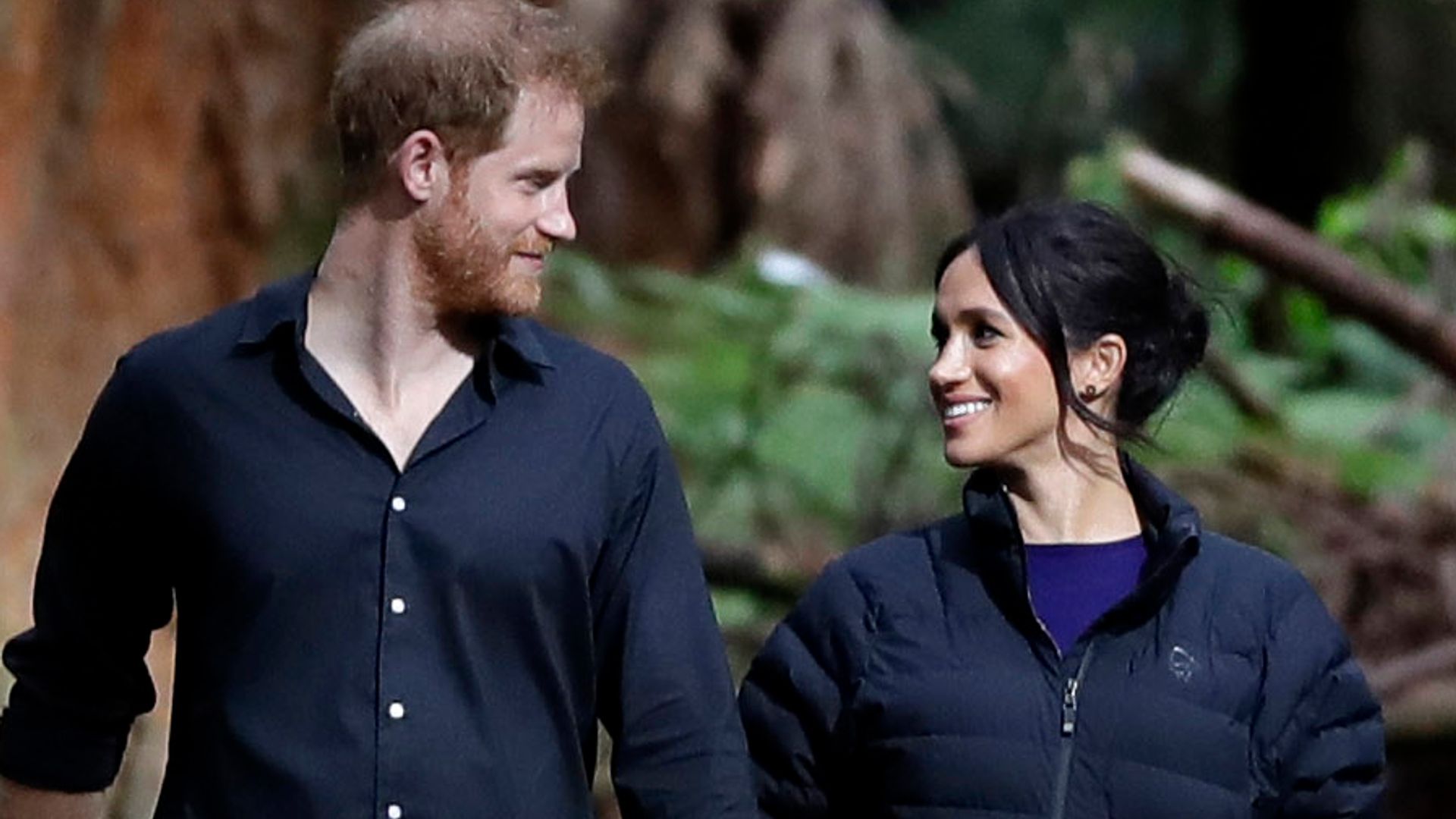 Prince Harry and Meghan walking through trees looking at each other