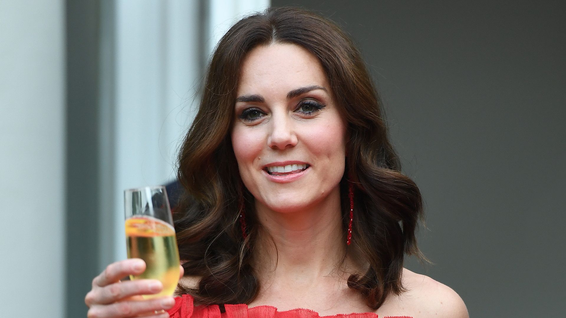Kate Middleton wearing red dress raises a glass of champagne during The Queen's Birthday Party at the British Ambassadorial Residenceduring an official visit to Poland and Germany on July 19, 2017 i