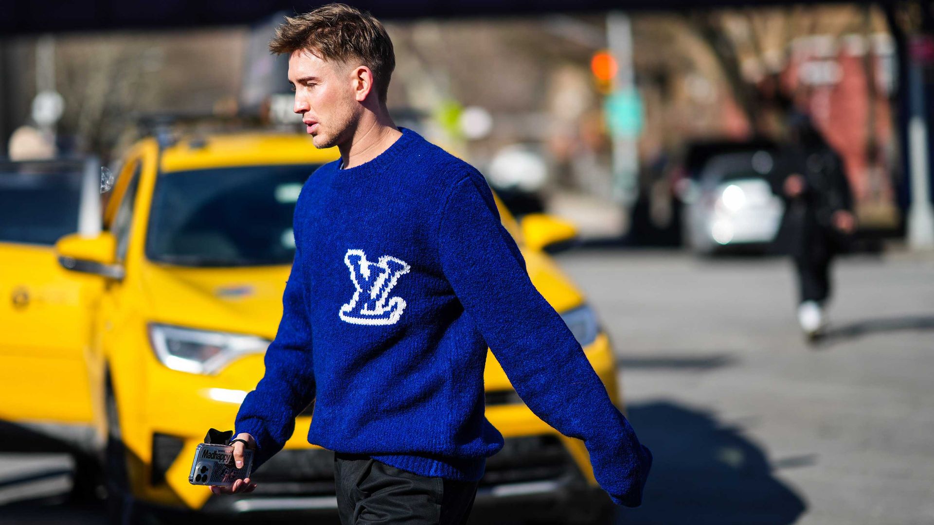 Fashion week goer wearing statement blue jumper in front of NY cab