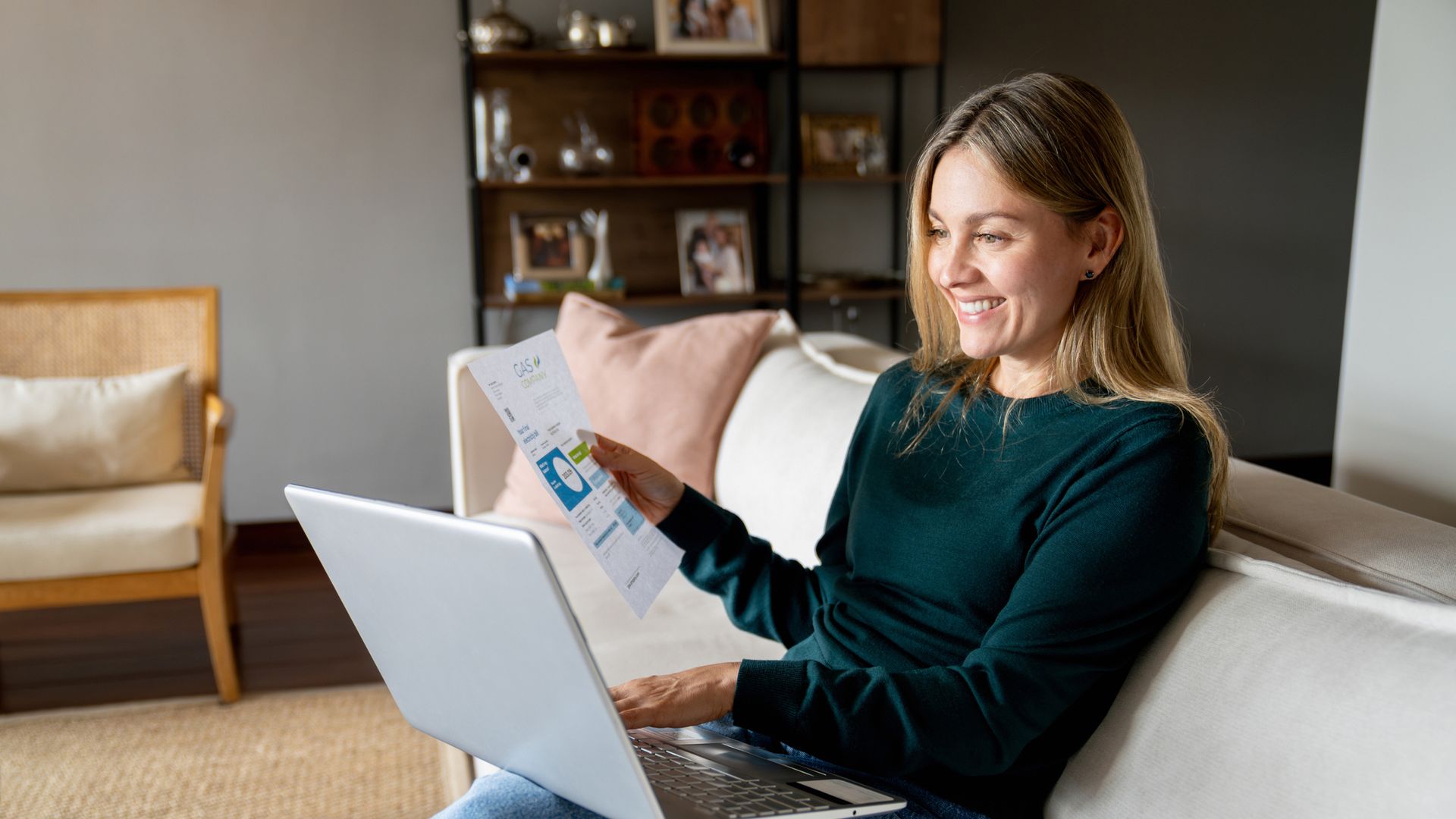 Happy woman at home paying bills online using her laptop