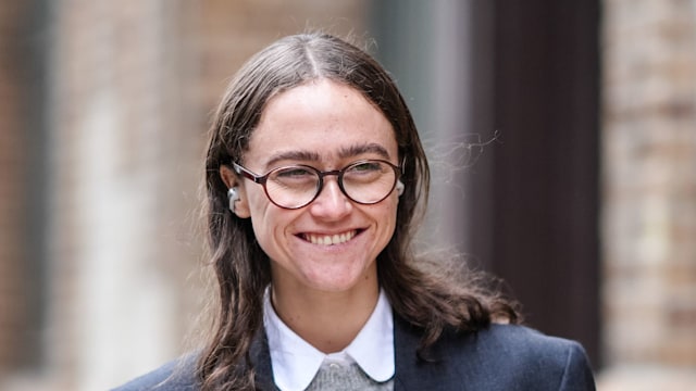 Ella Emhoff wears glasses, Apple airpods, a white shirt, a gray wool pullover, a black double breasted oversized blazer jacket ,  outside Proenza Schouler , during New York Fashion Week, on February 10, 2024 in New York City