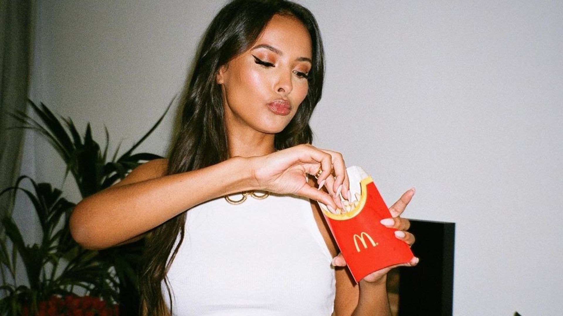 maya jama eating french fries in a white top
