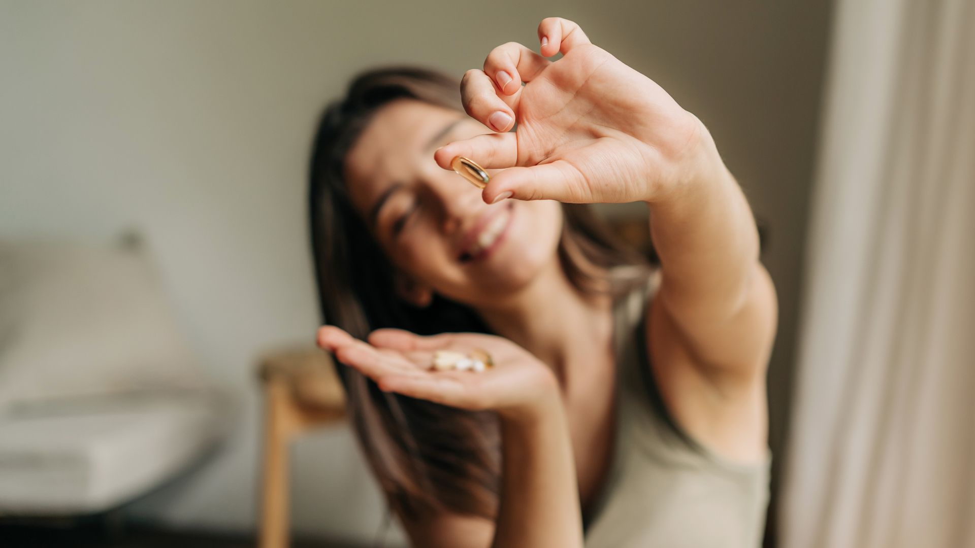 Happy smiling woman holding a pill in her hand.
