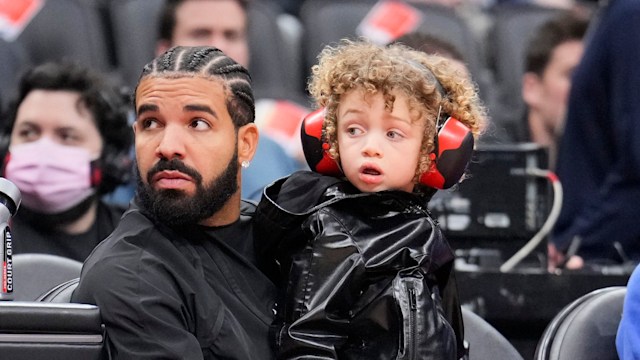 Drake sits with his son Adonis before the Toronto Raptors play the Philadelphia 76ers in their basketball game at the Scotiabank Arena on April 7, 2022 in Toronto, Ontario, Canada