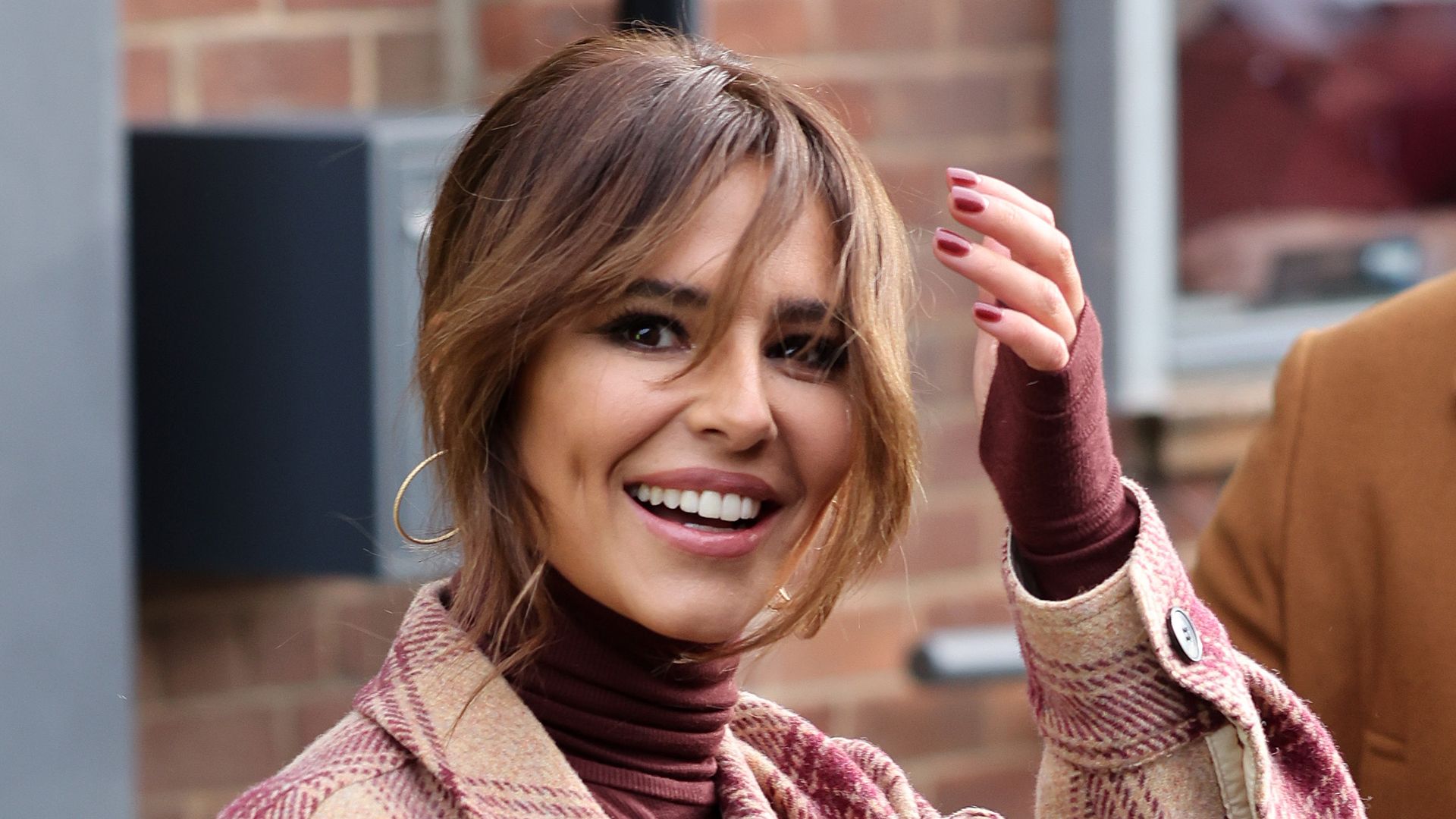 Cheryl in a tweed coat and maroon outfit