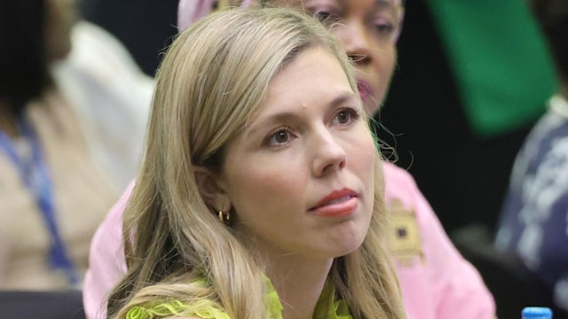 Carrie Johnson sitting in a lime-green dress