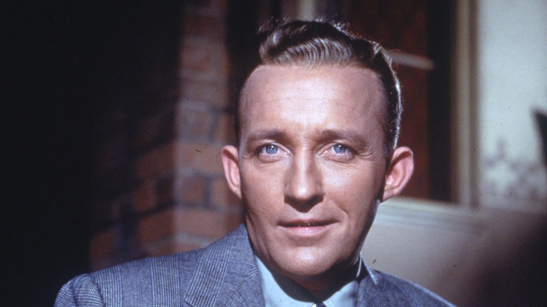 American actor and singer Bing Crosby poses for a portrait holding a pipe in his hand.