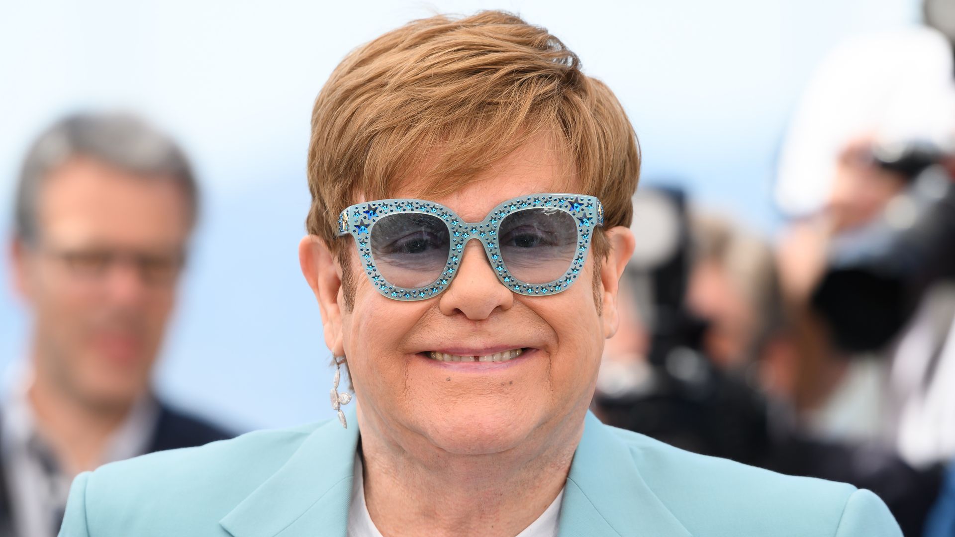 close-up pf man in blue sparkly glasses and blue blazer