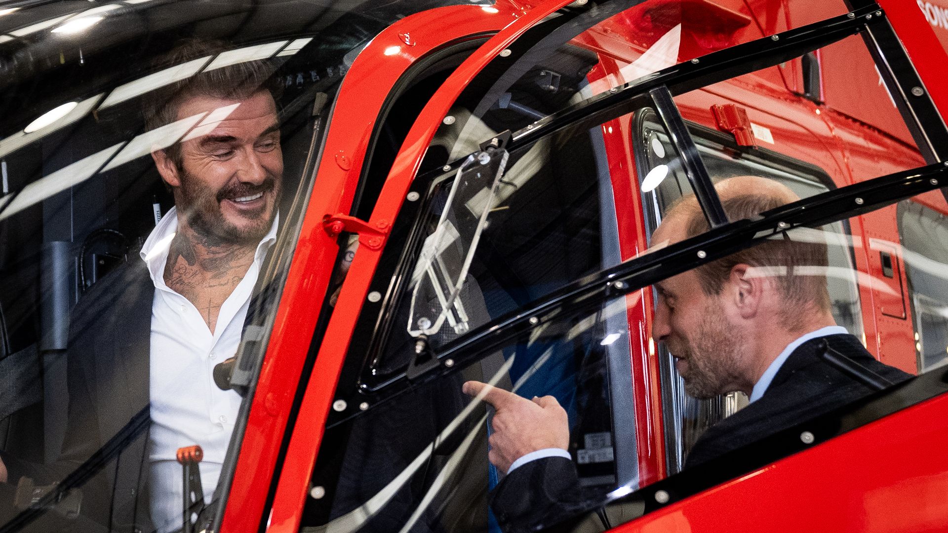 David Beckham sitting in a helicopter while laughing with Prince William
