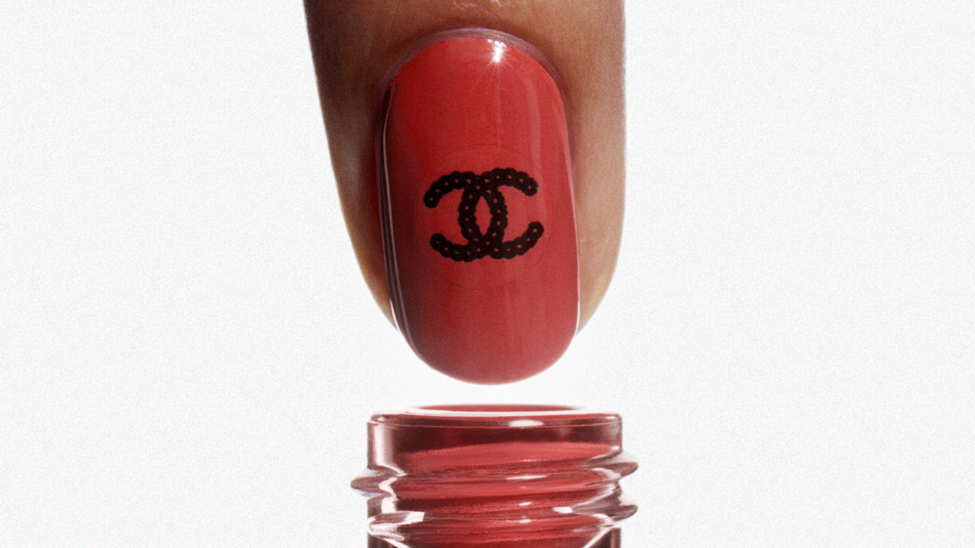 Warm red-coloured nail polish with black double-C sticker 