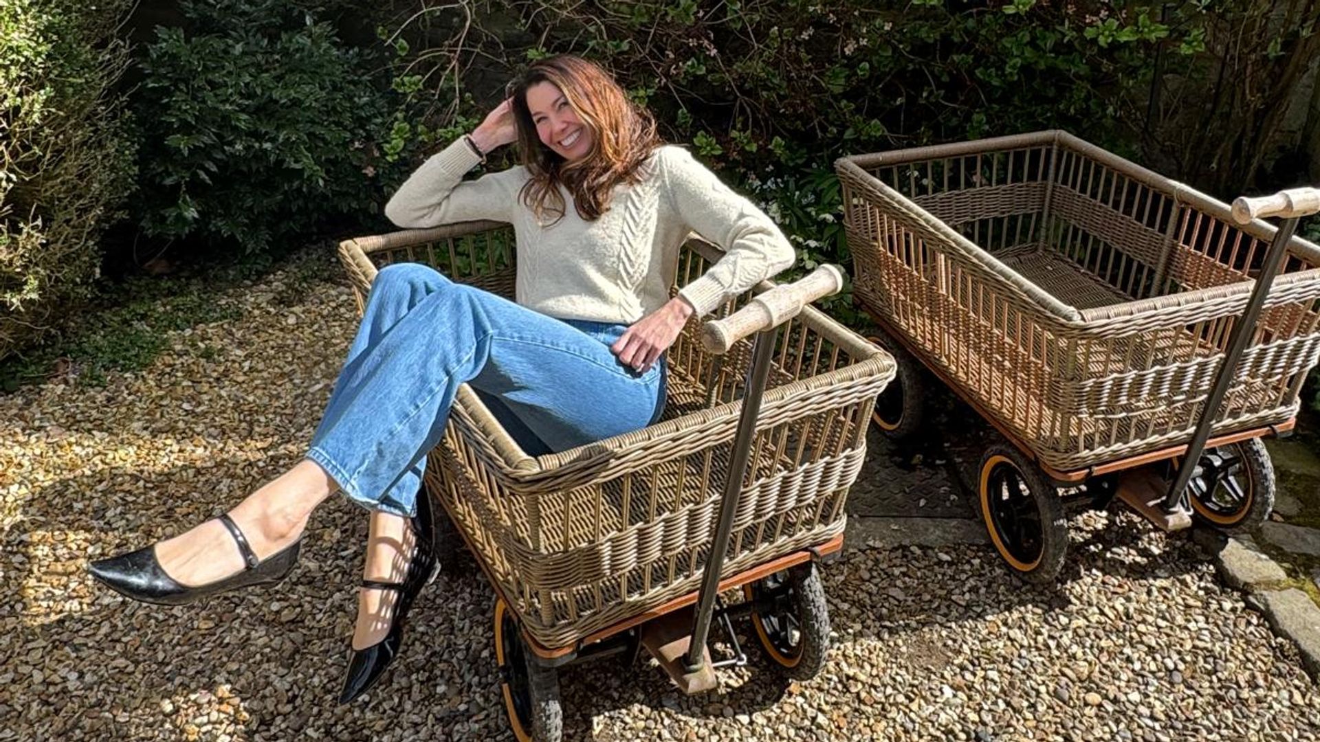 woman sitting in jeans in a basket on wheels 
