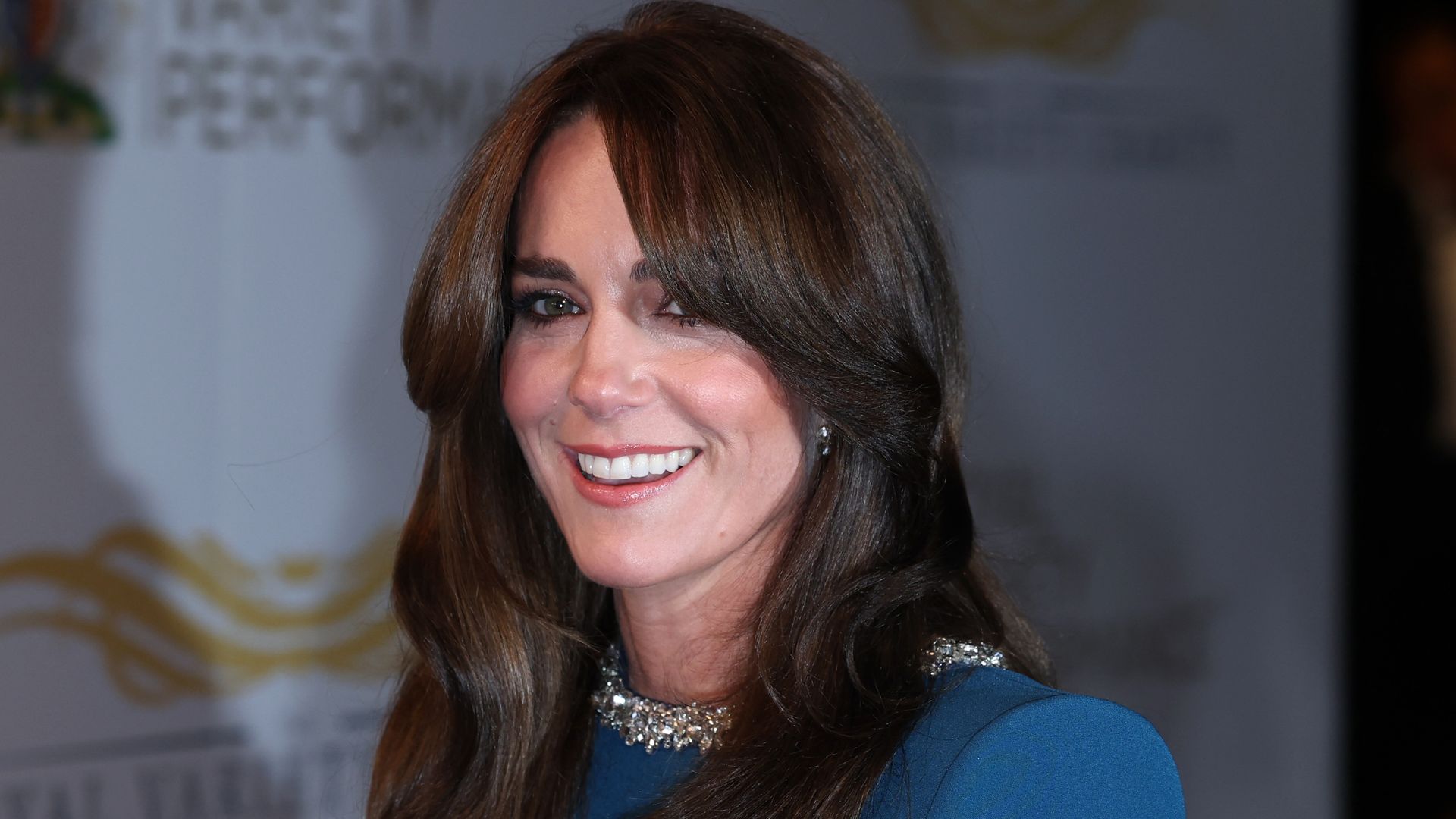 Kate Middleton smiling and wearing blue evening dress