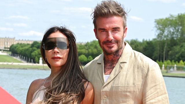 Victoria Beckham and David Beckham standing on the red carpet with water in the background while attending the "Le Chouchou" Jacquemus' Fashion Show at Chateau de Versailles
