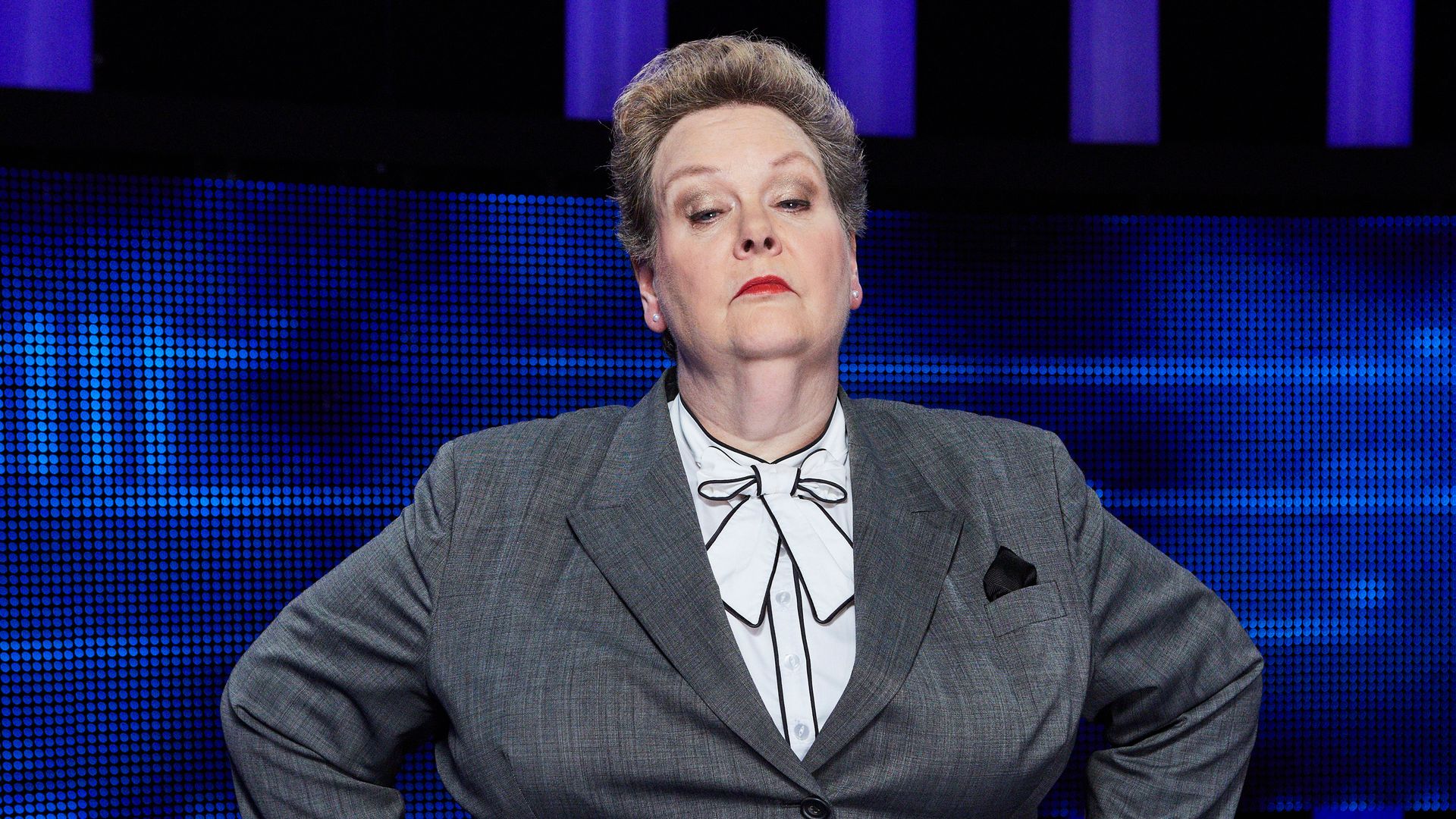 woman in grey suit with hands on hips in tv studio