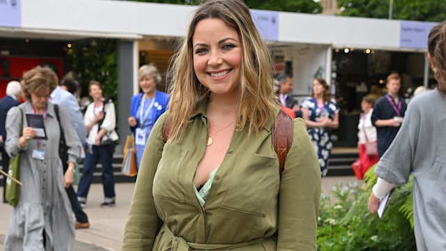 Charlotte Church smiling for a photo in front of flower festival stalls and guests