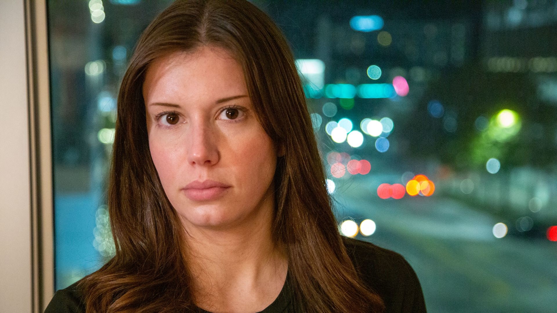 close-up of brunette woman standing against window