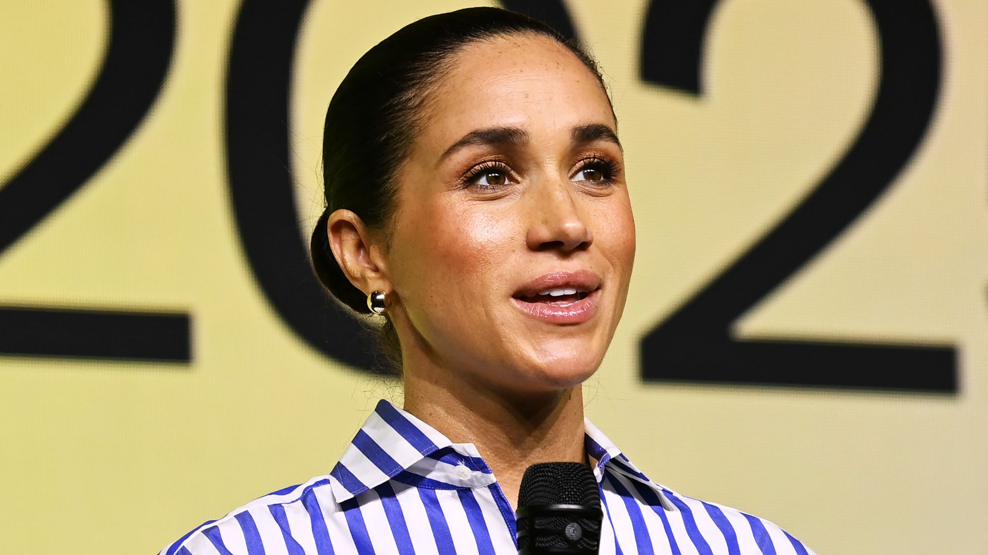 Meghan holding microphone in striped shirt