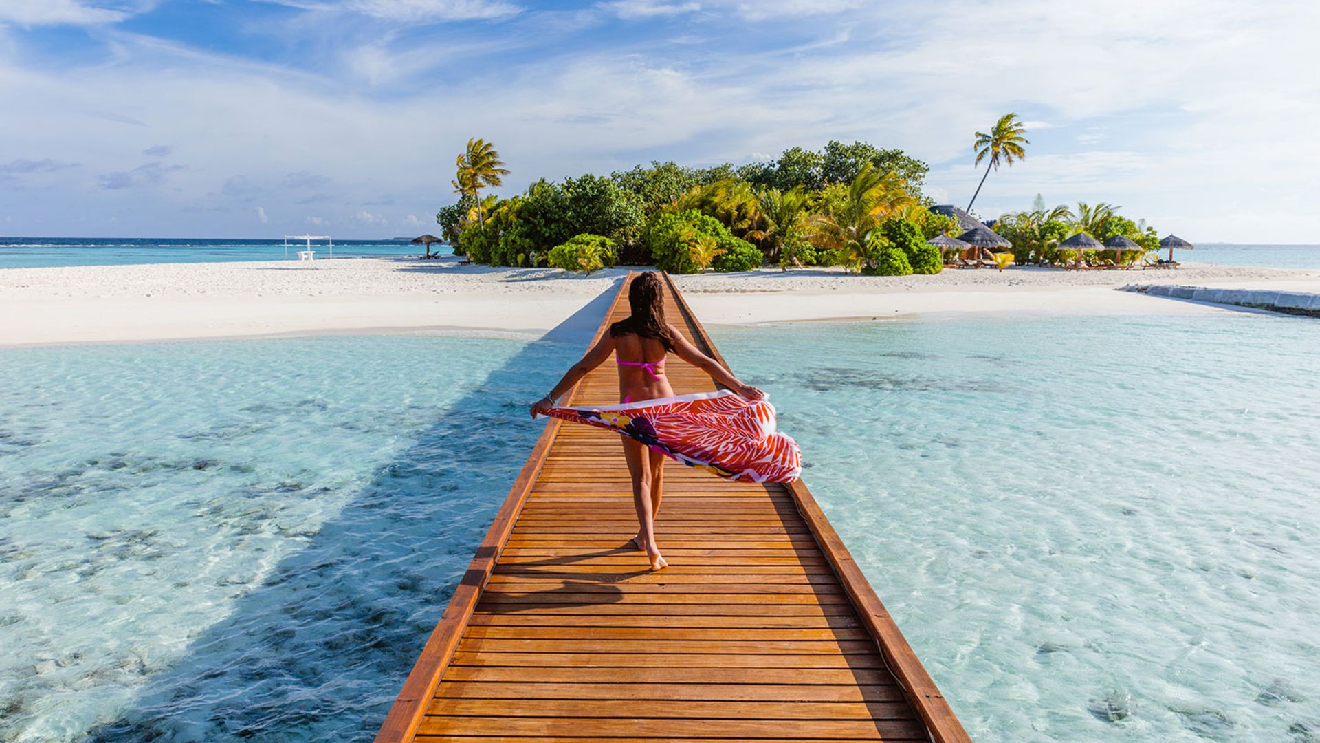 Woman with sarong walking on pier in the Maldives