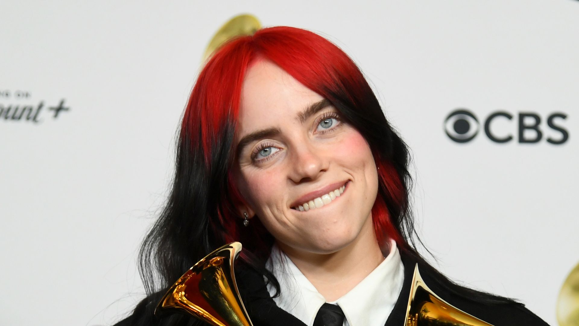 Billie Eilish strips down to a deeply plunging waistcoat with matching ...
