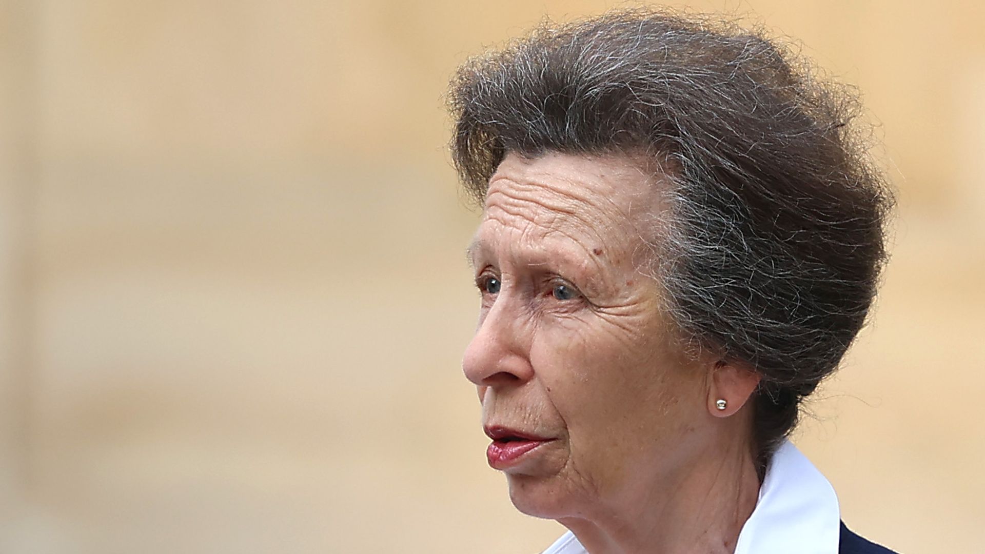 Princess Anne in a smart suit talking to two men in suits