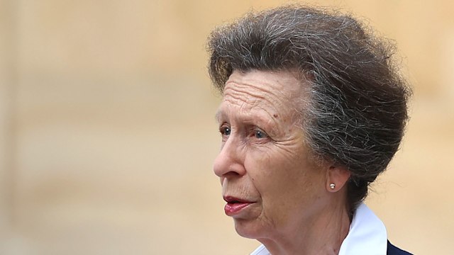 Princess Anne in a smart suit talking to two men in suits