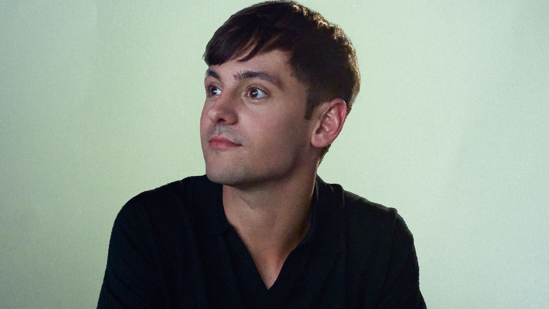 Tom Daley in a black shirt looking to his side