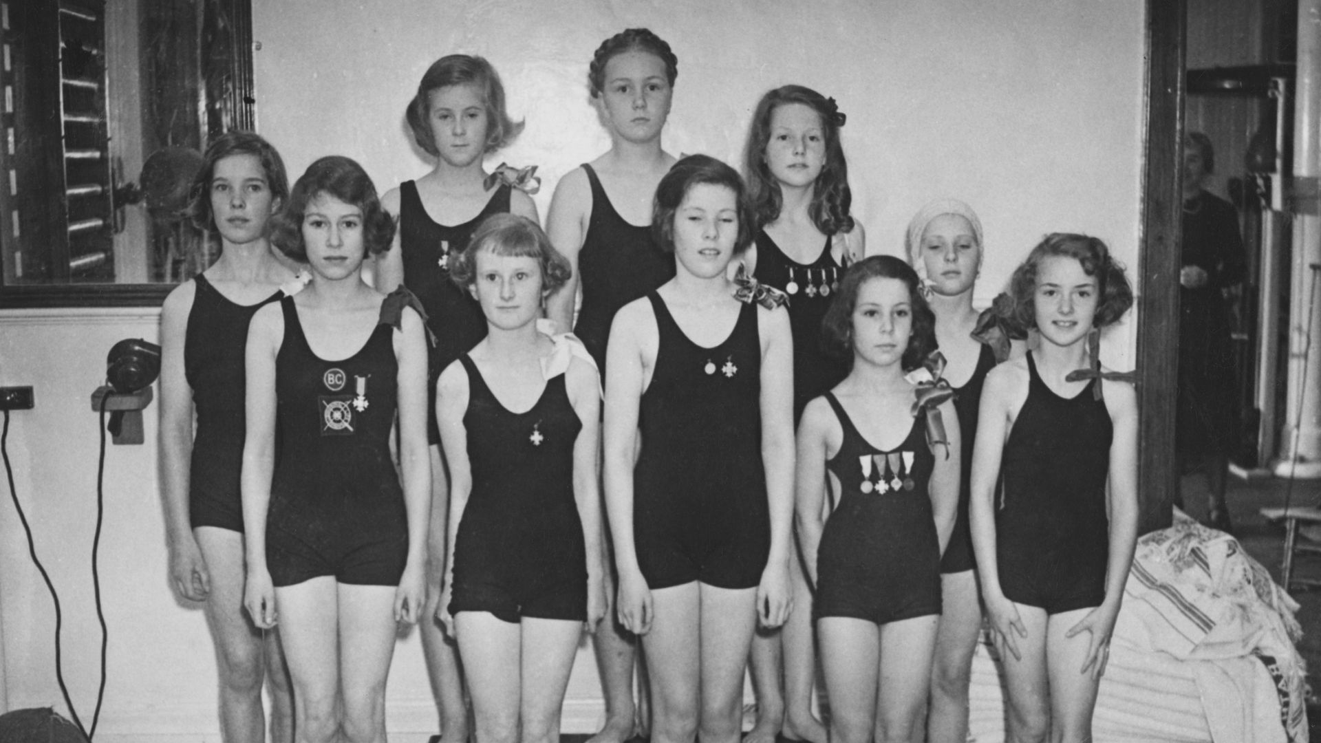 The Queen (front-left) with a group of young girls on a swimming team