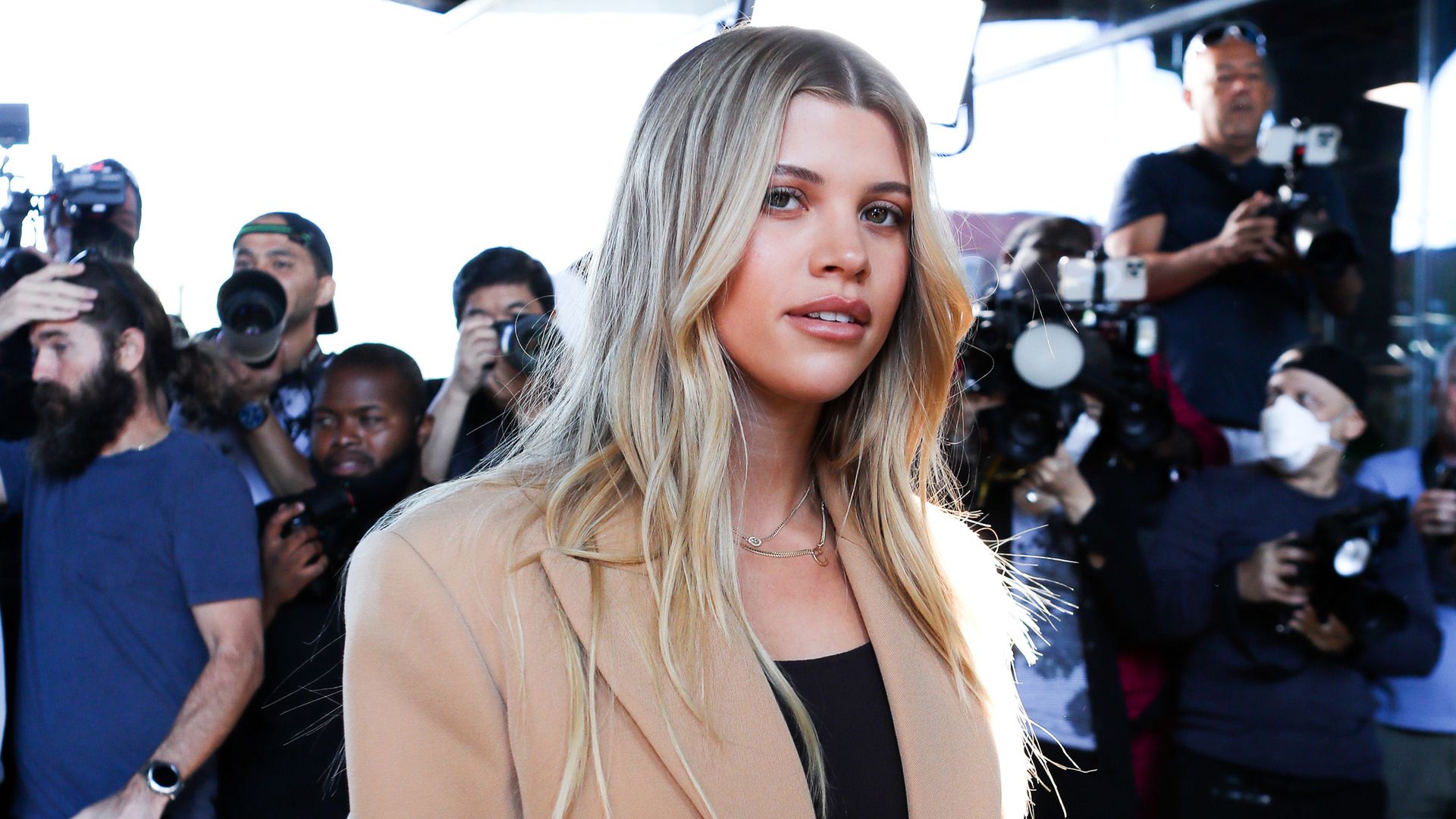 Sofia Richie in a nude coat looking at the camera