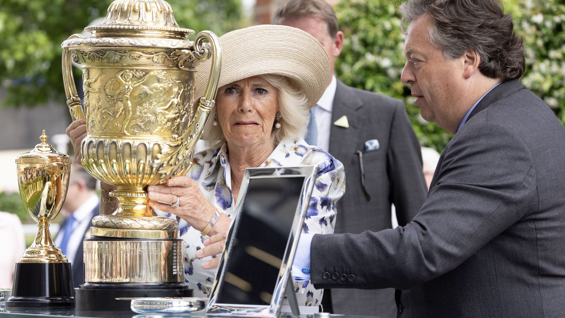 Queen Camilla pulling a face in front of a golden trophy