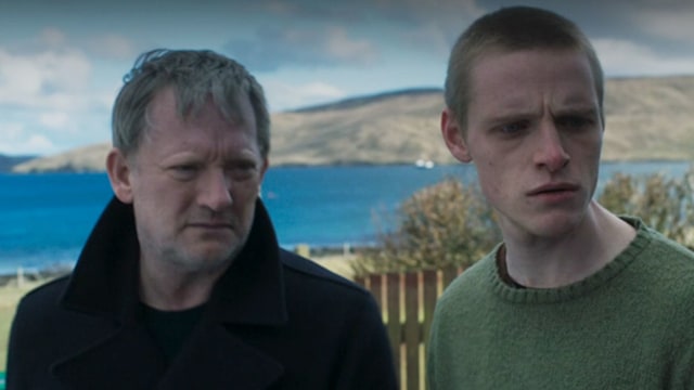 Close-up of two men in front of ocean backdrop