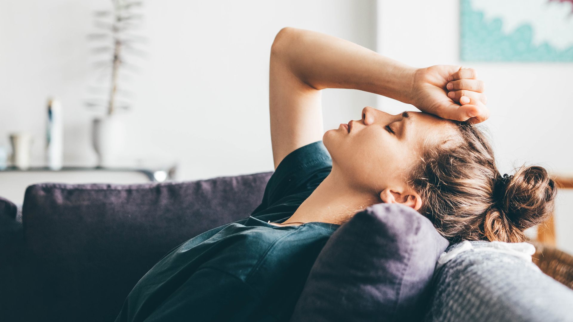 Sad and depressed woman sitting on sofa at home.