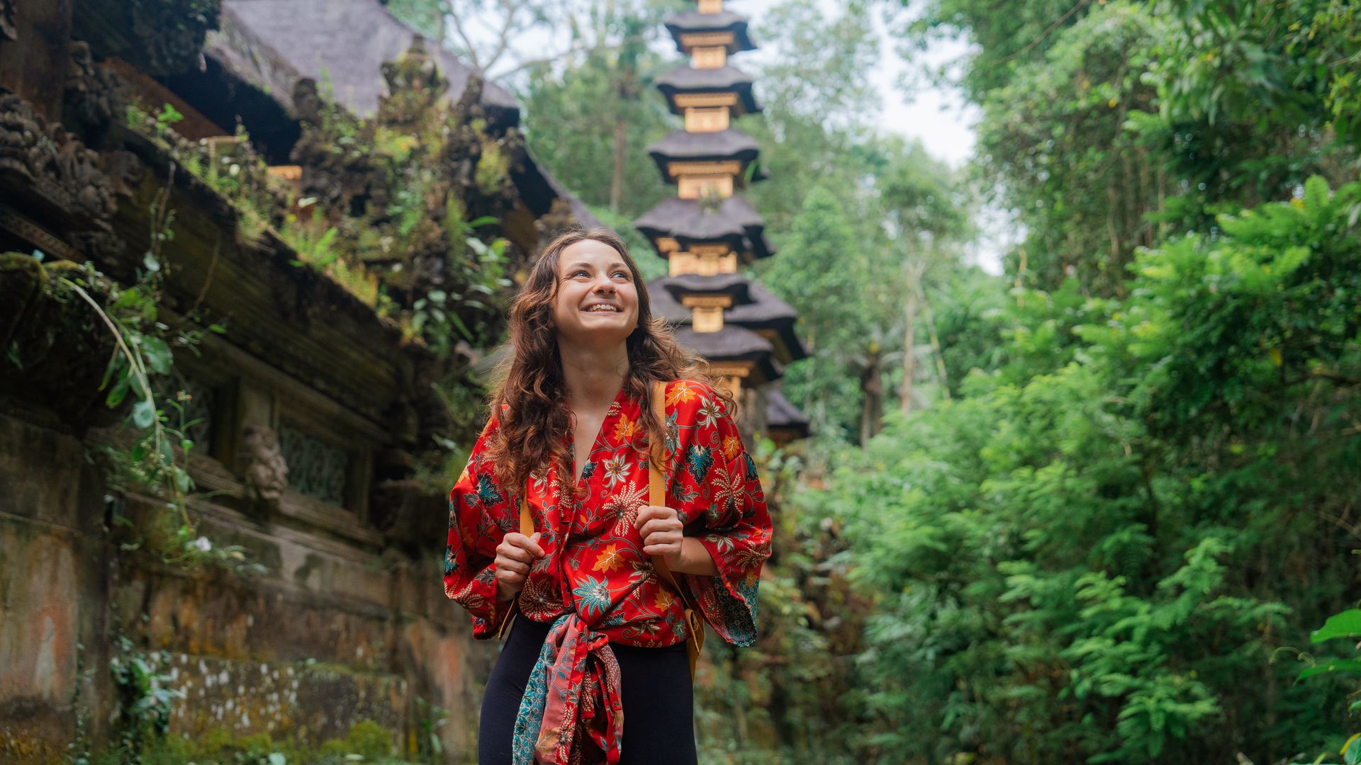 Woman walking past the temple in the jungles in Ubud, Bali