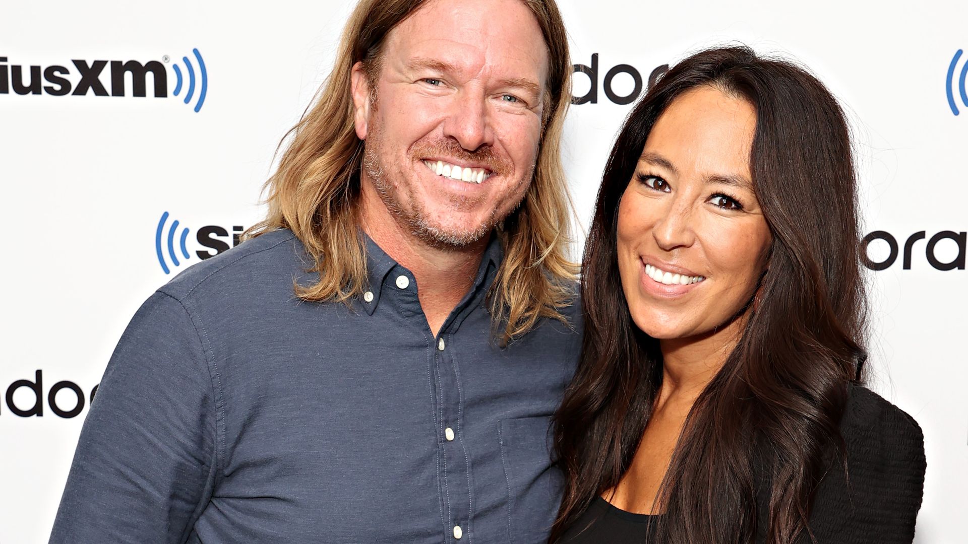 Chip and Joanna Gaines smiling at the camera on a red carpet