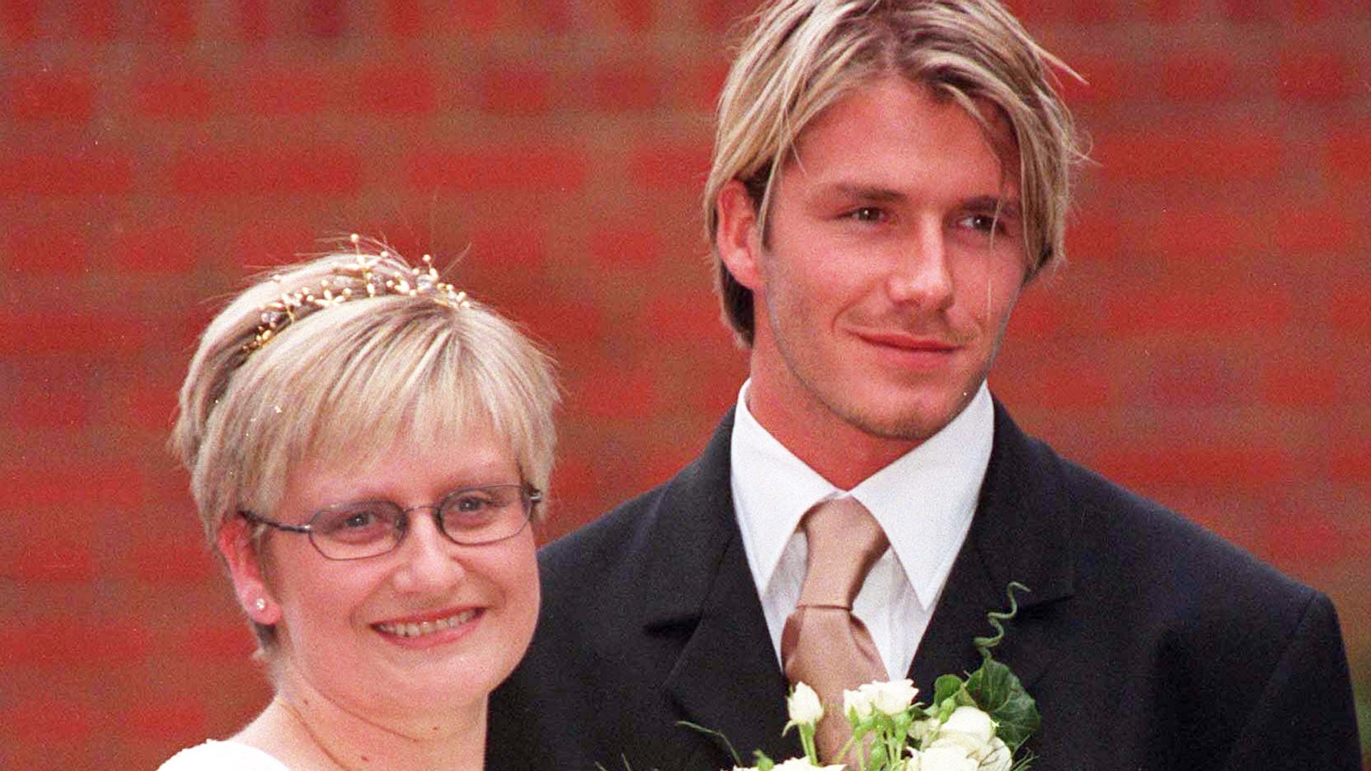 David Beckham in a suit with blonde hair smiling next to his sister Lynne on her wedding day