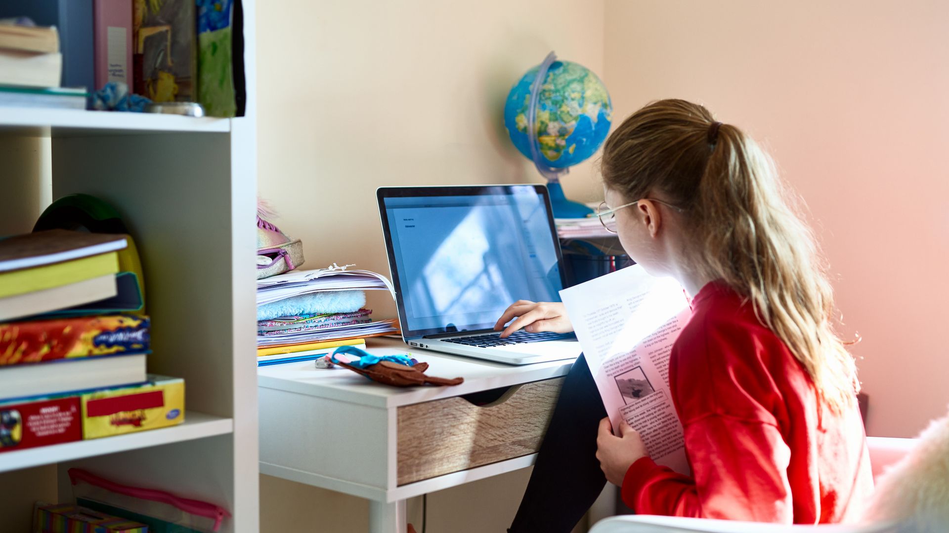 girl sitting at desk doing homework on computer