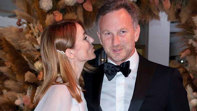 Geri Halliwell in a white dress leaning in to kiss Christian Horner in front of a flower arch