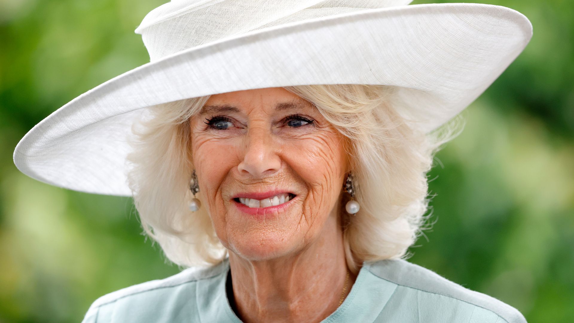 Camilla in light green dress and white hat