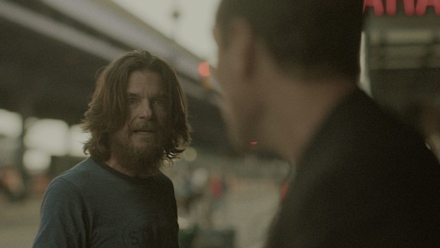 man with long hair looking at another man