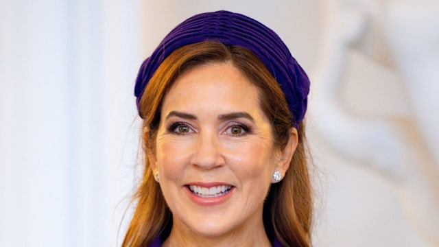 Queen Mary smiling in purple dress and headband