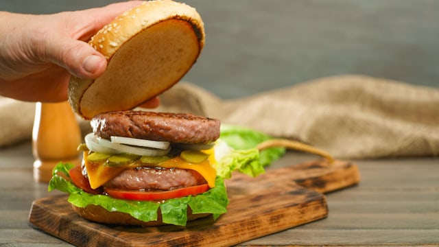 An open burger on a wooden chopping board