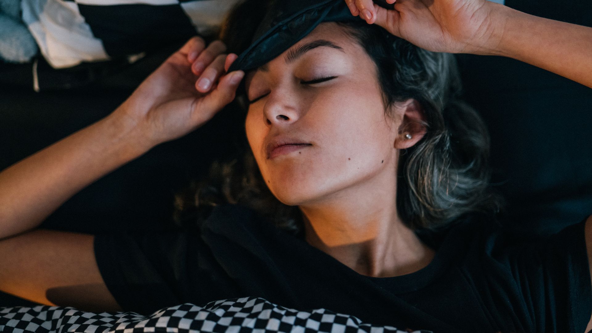Woman waking up in bed with sleep mask on
