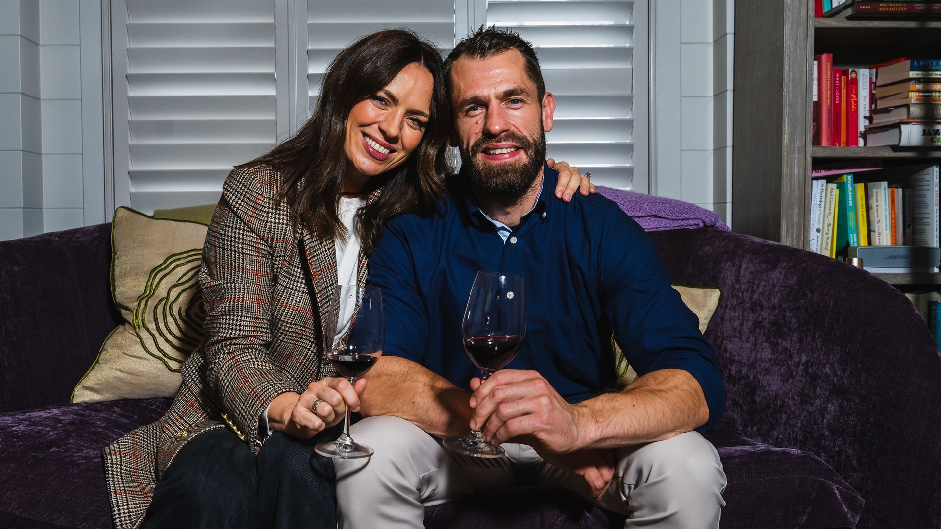 Liz Fletcher and Kelvin Fletcher sitting on a sofa with wine glasses
