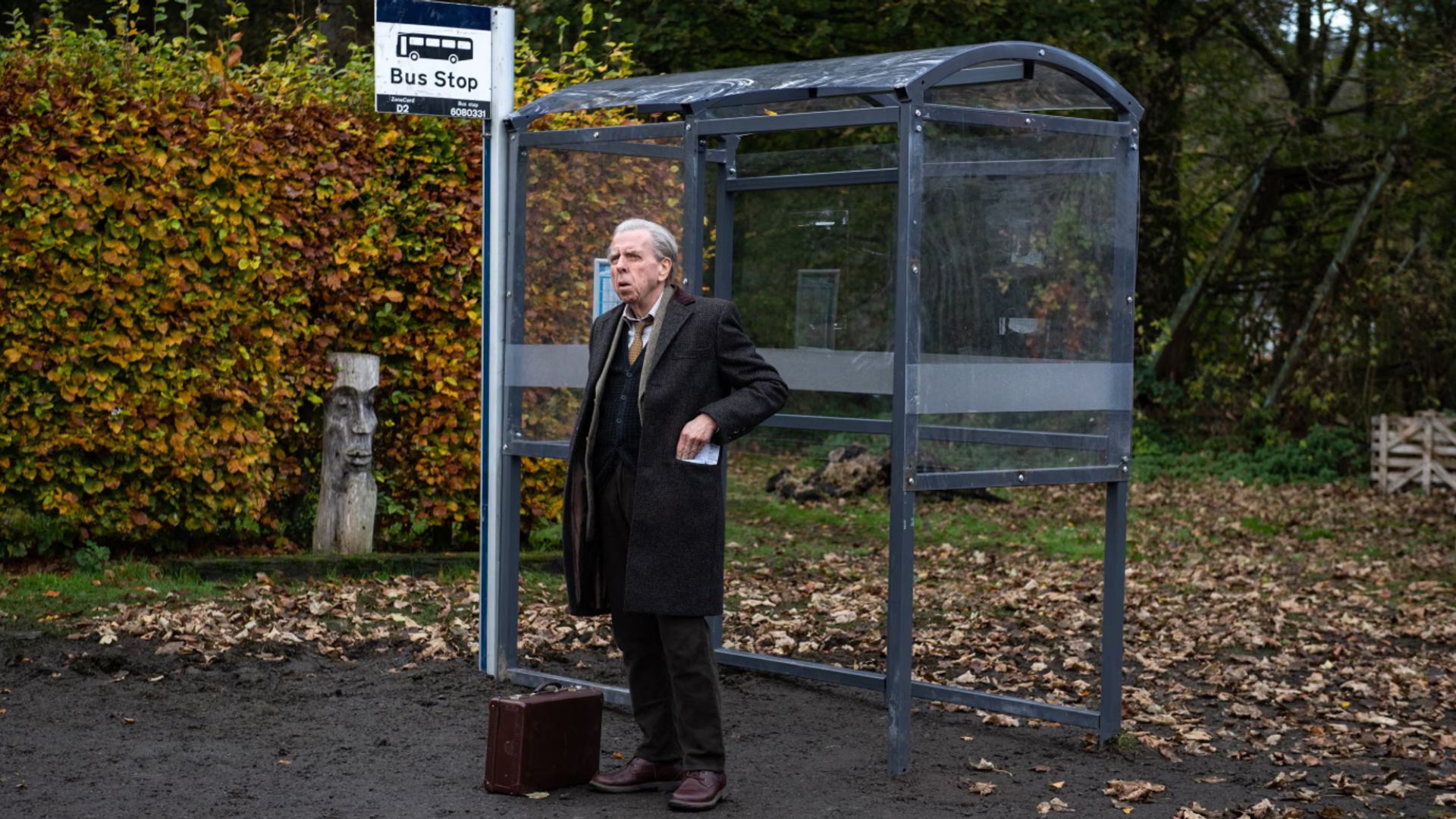 Timothy Spall standing at a bus stop in The Last Bus