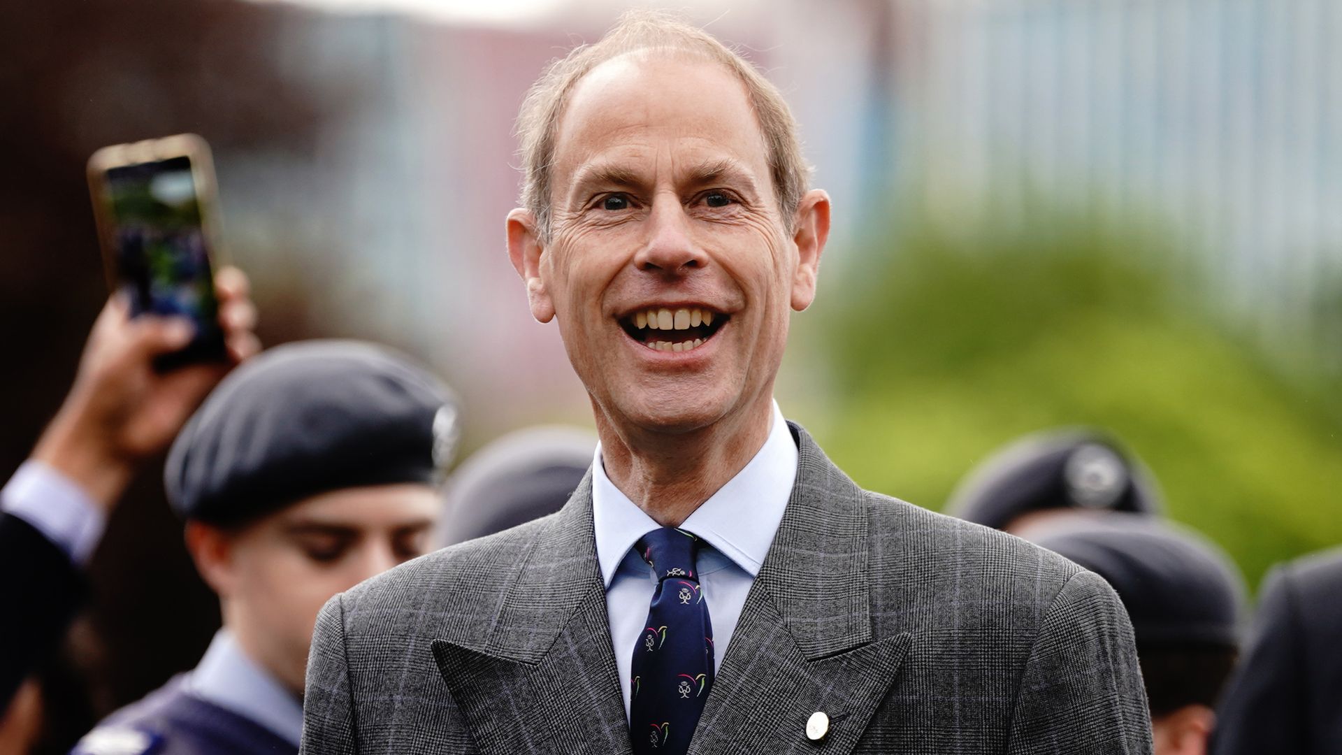 Prince Edward smiling widely in a tweed suit