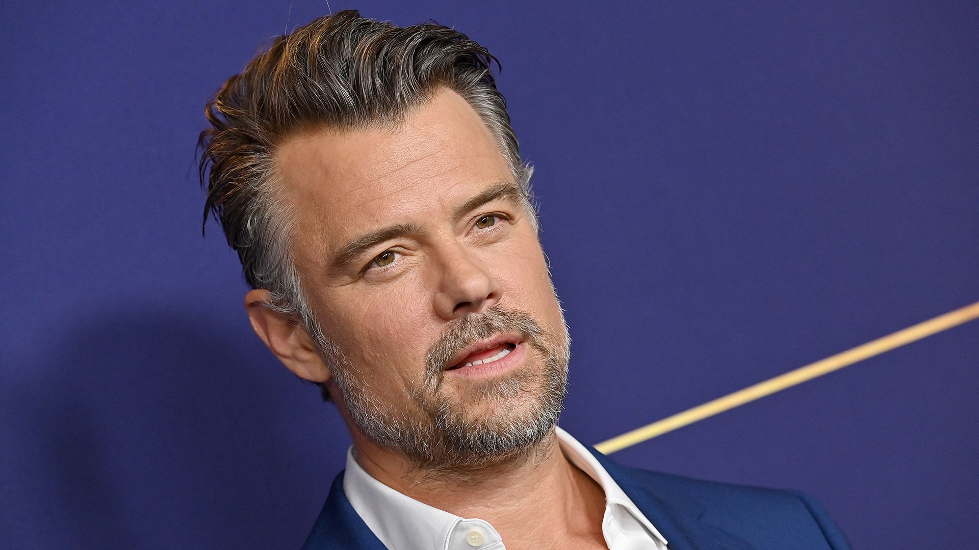 Close up of Josh Duhamel wearing a navy suit and white shirt